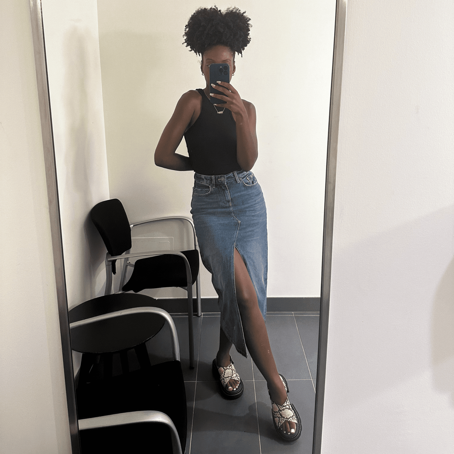 Byrdie social media editor Jasmine Phillips wearing a black tank top and light wash denim maxi skirt in a mirror selfie.