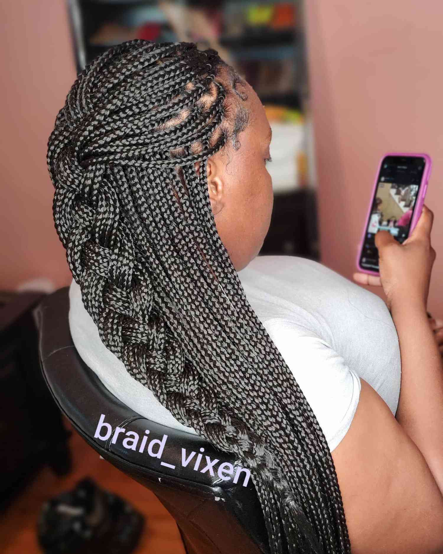 A woman with box braids, half plaited, half down 