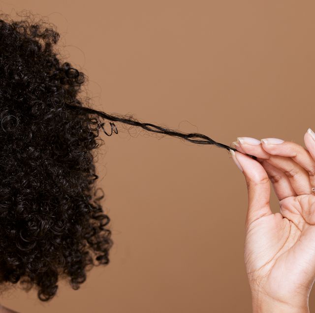 hair care, beauty and black woman hand with curly hair on brown background in studio hair salon, wellness and girl holding curl marketing hair treatment products for growth, natural and healthy hair